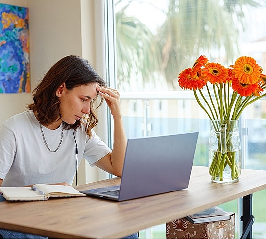 Person stressed while working on laptop at home.