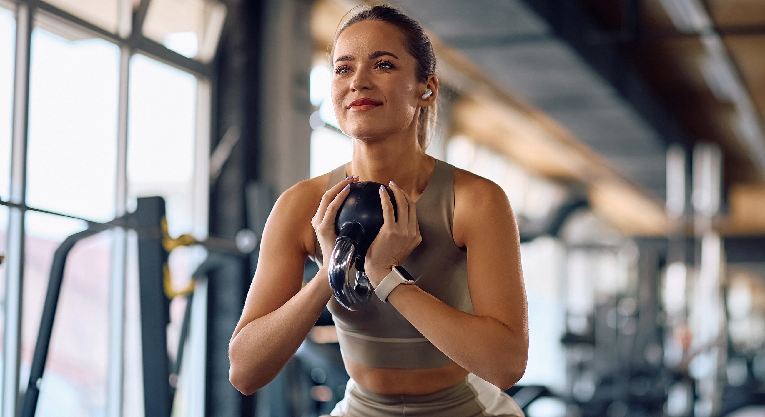 Woman lifting kettlebell in gym environment